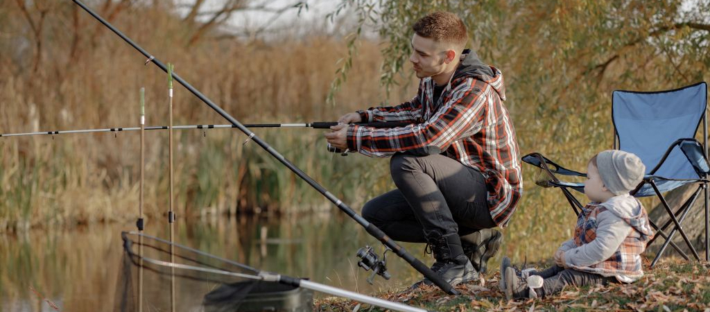 Family by the river. Guy in a red shirt. Father with in a fishing.